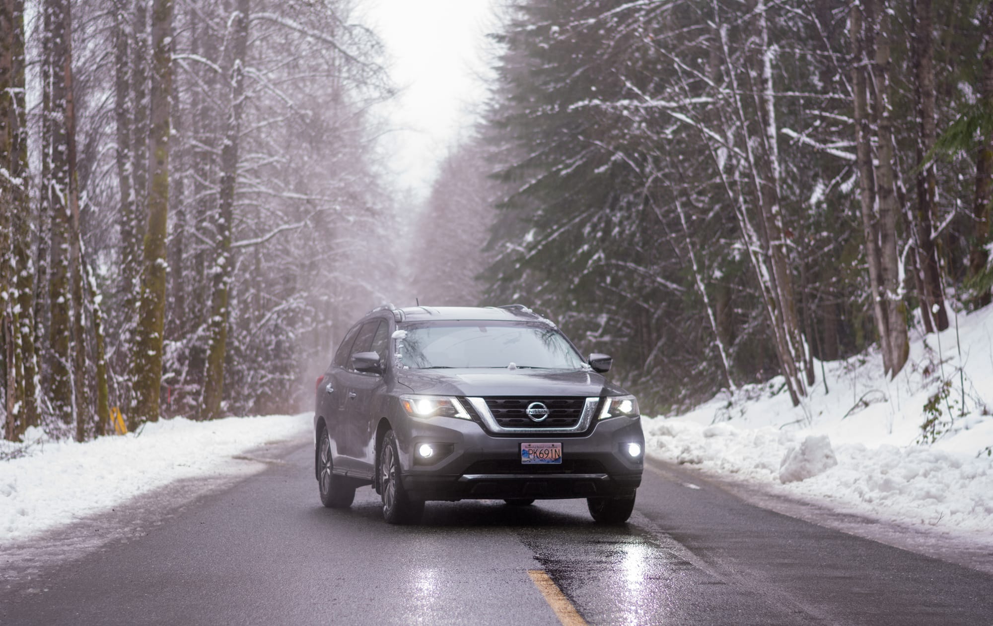 Photo of a Nissan Pathfinder in the middle of an abandoned snowy road, with snow covered trees on both sides of the road and snow banks encroaching on the road. The vehicle is parked in the center of the road at a slight angle, facing towards the camera, with all the lights on. It has a BC parks mountain range license plate on the front. Photo of a Nissan Pathfinder in the middle of an abandoned snowy road, with snow covered trees on both sides of the road and snow banks encroaching on the road. The vehicle is parked in the center of the road at a slight angle, facing towards the camera, with all the lights on. It has a BC parks mountain range license plate on the front.
